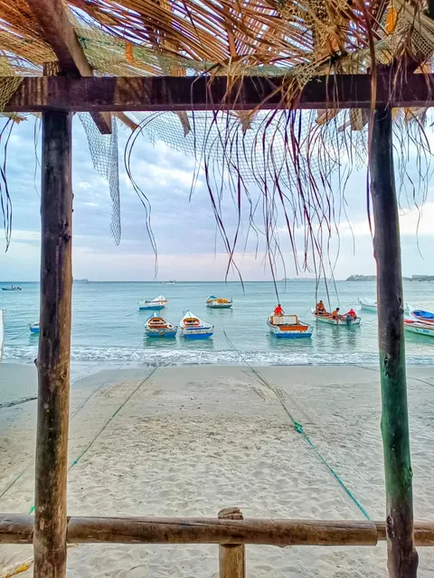 Encantadora playa de la Isla de Margarita con botes coloridos y vista desde una palapa.