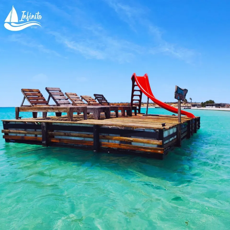 Plataforma flotante con tumbonas y tobogán rojo en las aguas cristalinas de la Isla de Cubagua.